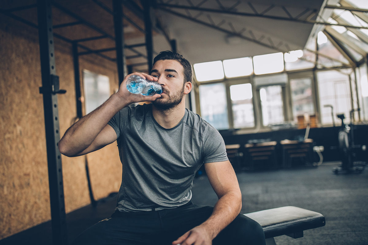 man on bench, drinking water after training